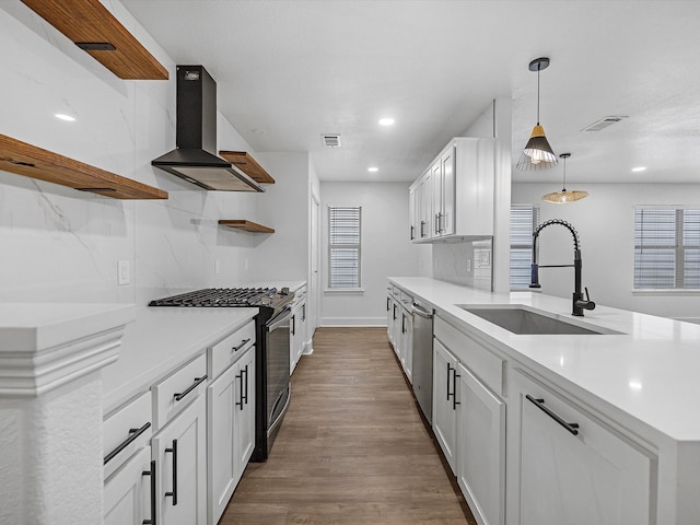 kitchen with dark wood-type flooring, white cabinets, exhaust hood, black range with gas cooktop, and sink