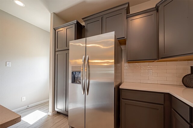 kitchen with decorative backsplash, light hardwood / wood-style floors, and stainless steel refrigerator with ice dispenser