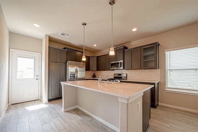 kitchen with stainless steel appliances, plenty of natural light, pendant lighting, and decorative backsplash