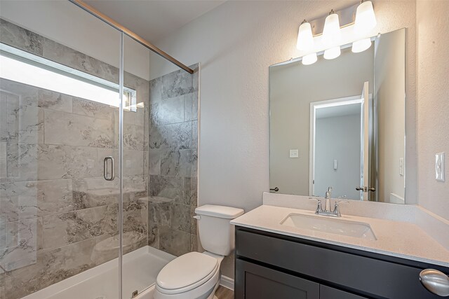 bathroom featuring vanity, a shower with door, and toilet