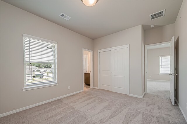 unfurnished bedroom featuring light carpet and a closet