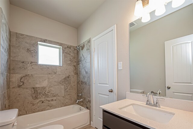 full bathroom featuring tiled shower / bath combo, vanity, and toilet