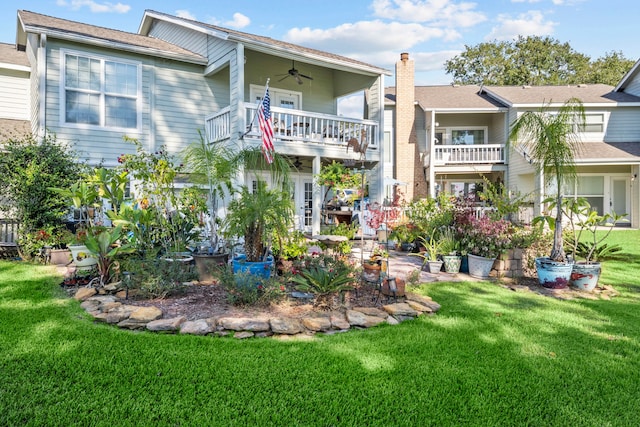 back of property featuring ceiling fan, a balcony, and a lawn