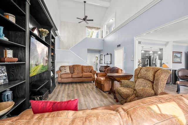 living room with light hardwood / wood-style floors, ornamental molding, ceiling fan, and high vaulted ceiling