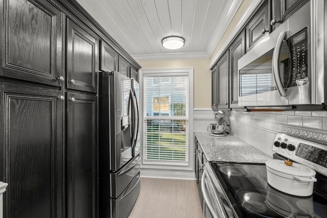 kitchen with light stone counters, hardwood / wood-style flooring, decorative backsplash, stainless steel appliances, and ornamental molding