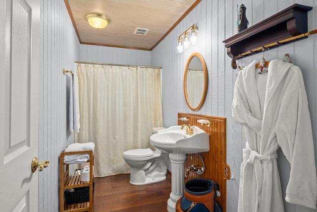 bathroom featuring crown molding, wood walls, toilet, and wood-type flooring