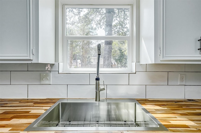 interior details featuring white cabinetry, sink, and decorative backsplash