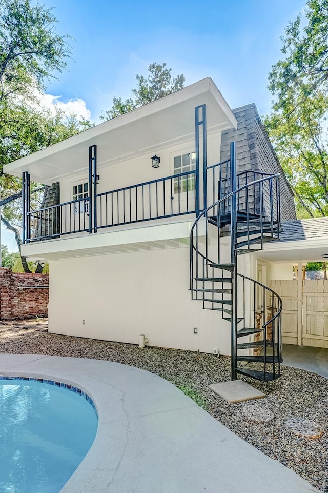 back of property featuring a fenced in pool and a balcony