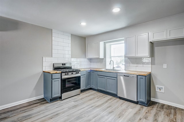 kitchen featuring white cabinetry, stainless steel appliances, sink, and butcher block countertops