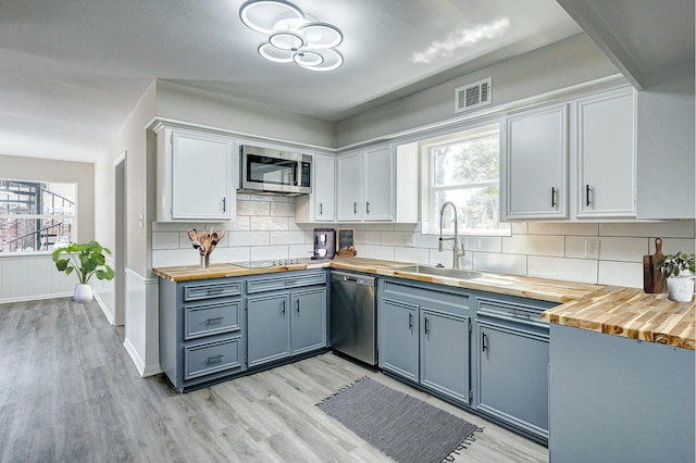 kitchen with stainless steel appliances, tasteful backsplash, white cabinets, and wood counters