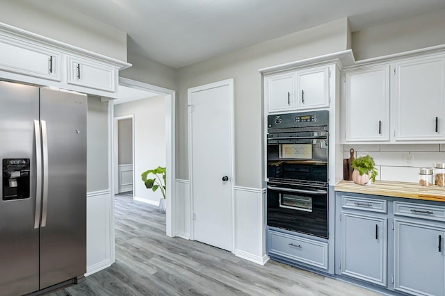 kitchen featuring stainless steel fridge, double oven, backsplash, light hardwood / wood-style floors, and white cabinets