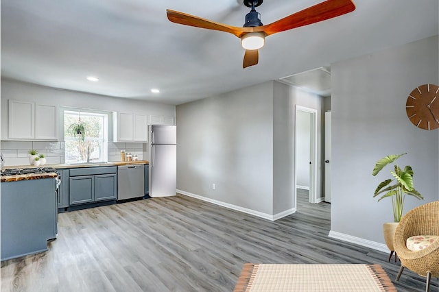 kitchen with sink, light hardwood / wood-style flooring, appliances with stainless steel finishes, gray cabinets, and backsplash