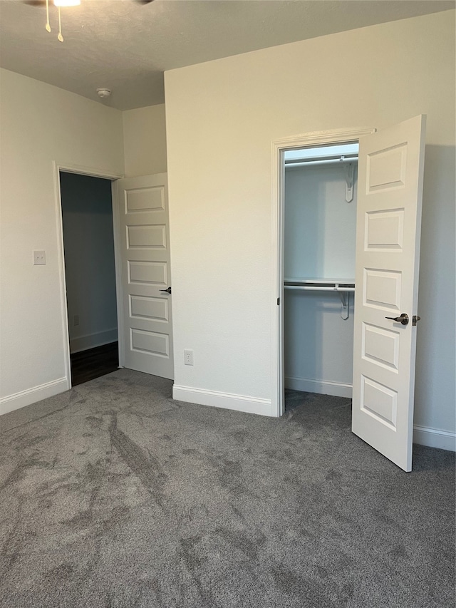 unfurnished bedroom with a closet and dark colored carpet