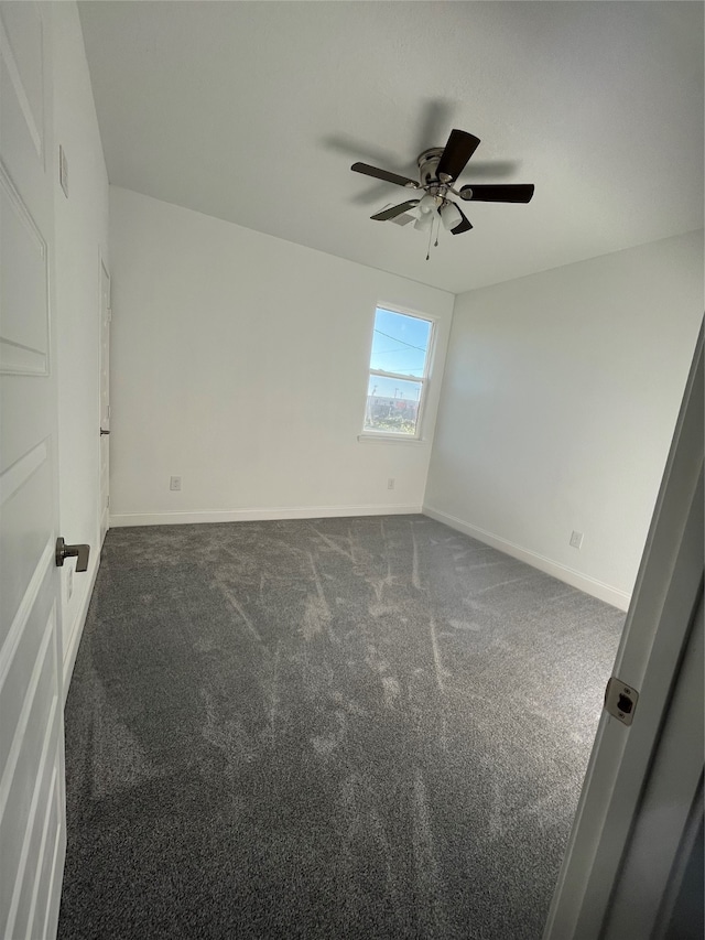 spare room featuring dark carpet and ceiling fan