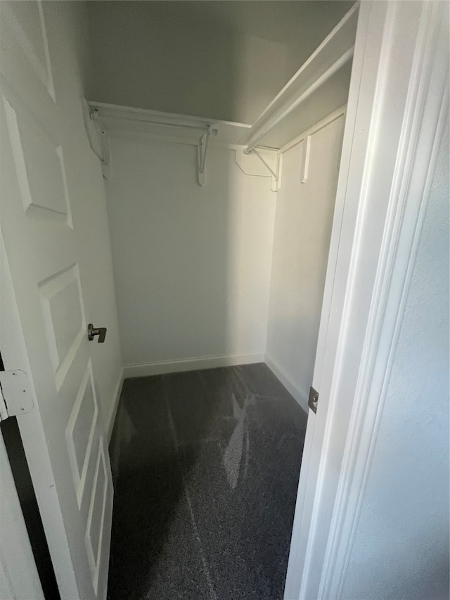 walk in closet featuring dark colored carpet