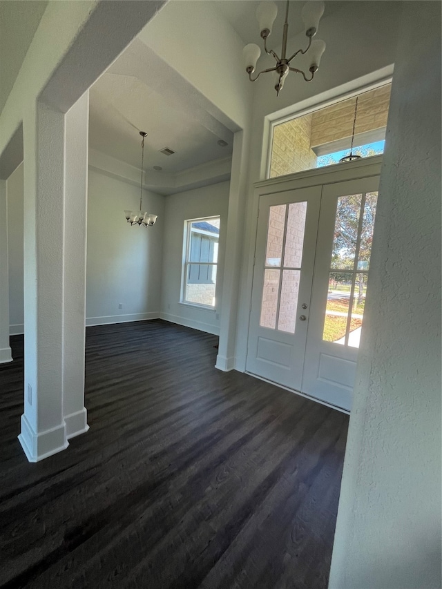 interior space with a wealth of natural light, french doors, a notable chandelier, and dark hardwood / wood-style flooring