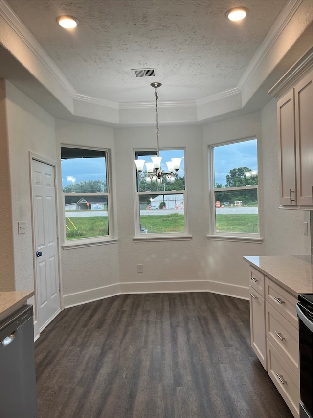 unfurnished dining area featuring ornamental molding, dark wood-type flooring, a tray ceiling, and an inviting chandelier