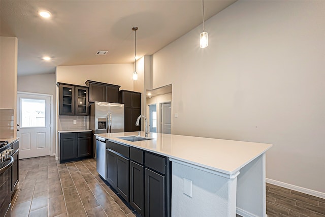 kitchen featuring lofted ceiling, dark hardwood / wood-style floors, sink, pendant lighting, and a center island with sink