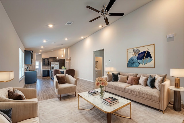 living room with light hardwood / wood-style floors, high vaulted ceiling, and ceiling fan