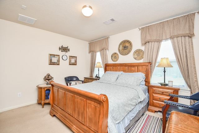 bedroom with light carpet, a textured ceiling, and multiple windows