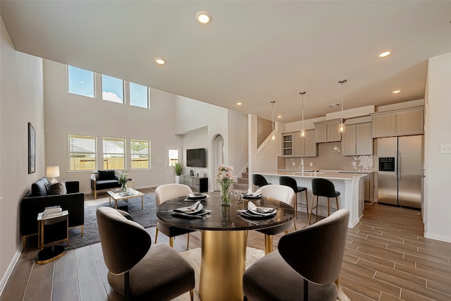 dining room with a high ceiling, light wood-type flooring, and sink