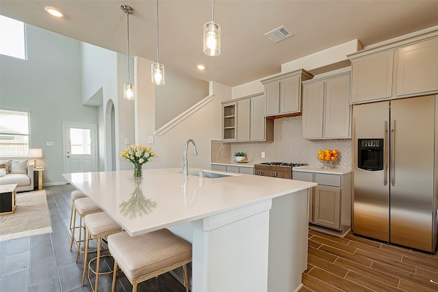 kitchen featuring pendant lighting, dark wood-type flooring, sink, stainless steel appliances, and backsplash