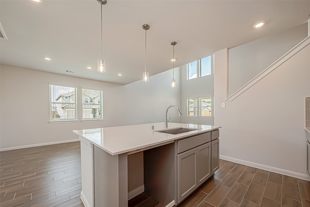 kitchen with pendant lighting, a center island with sink, sink, and dark hardwood / wood-style flooring