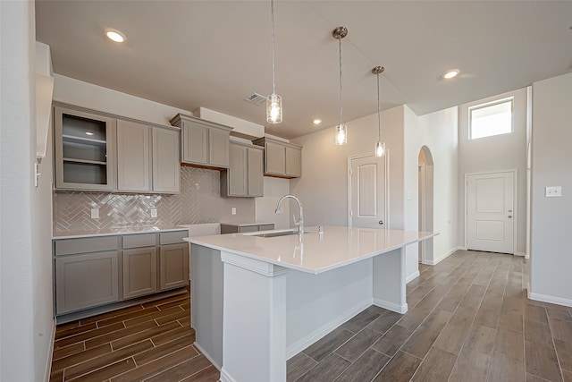 kitchen featuring a center island with sink, dark wood-type flooring, sink, and decorative light fixtures