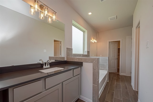 bathroom with tiled tub and vanity