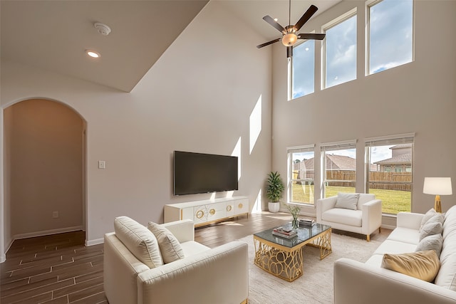 living room featuring a towering ceiling, ceiling fan, and hardwood / wood-style floors