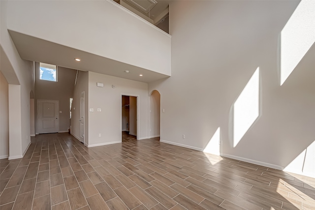 unfurnished living room featuring a towering ceiling and wood-type flooring