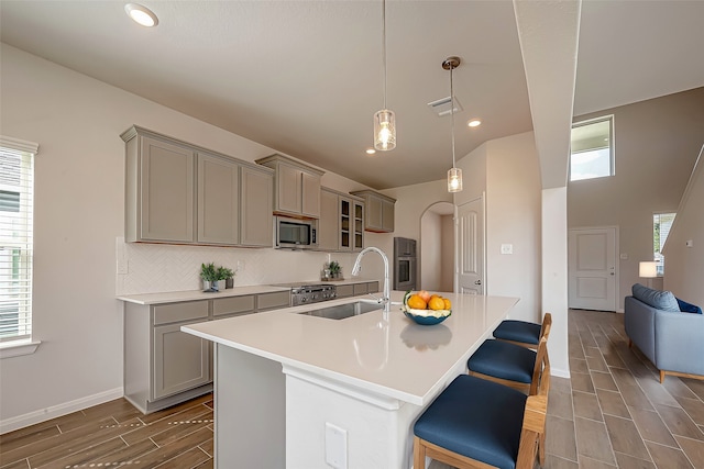 kitchen with gray cabinets, hardwood / wood-style floors, a breakfast bar area, sink, and stainless steel appliances