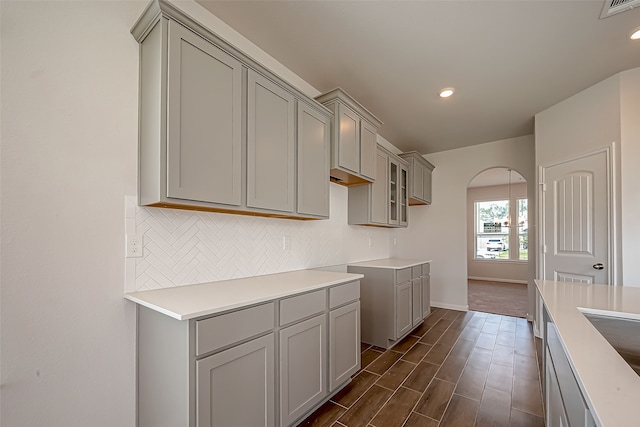 kitchen with dark wood-type flooring, decorative backsplash, and gray cabinetry