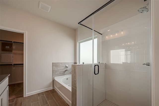 bathroom with wood-type flooring, vanity, and plus walk in shower