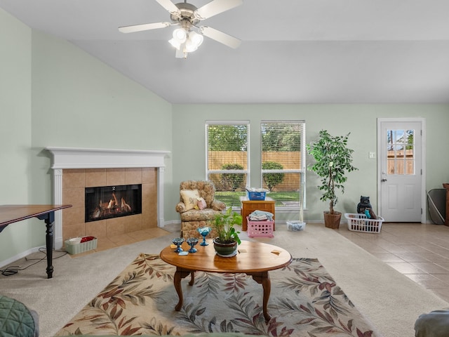 tiled living room with ceiling fan, a tile fireplace, vaulted ceiling, and a wealth of natural light