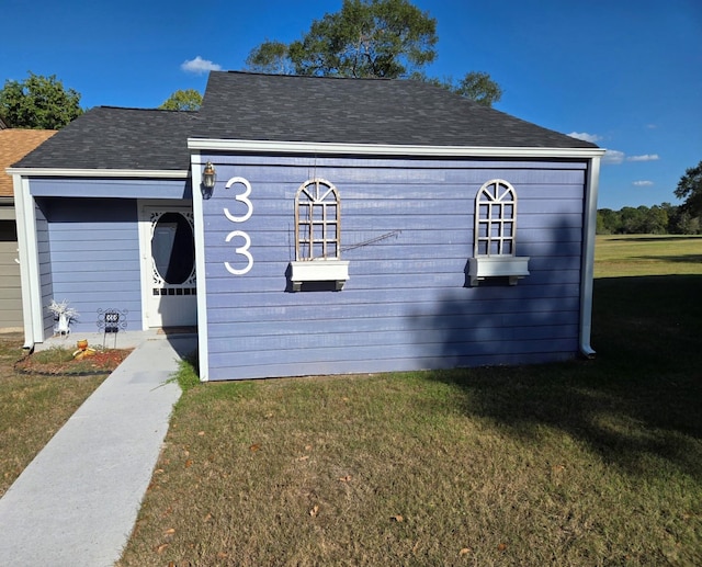 view of front facade with roof with shingles and a front lawn