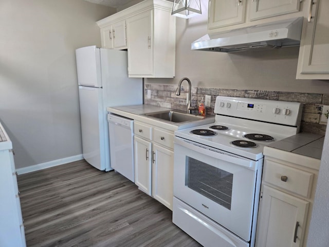 kitchen with white appliances, white cabinets, under cabinet range hood, a sink, and baseboards