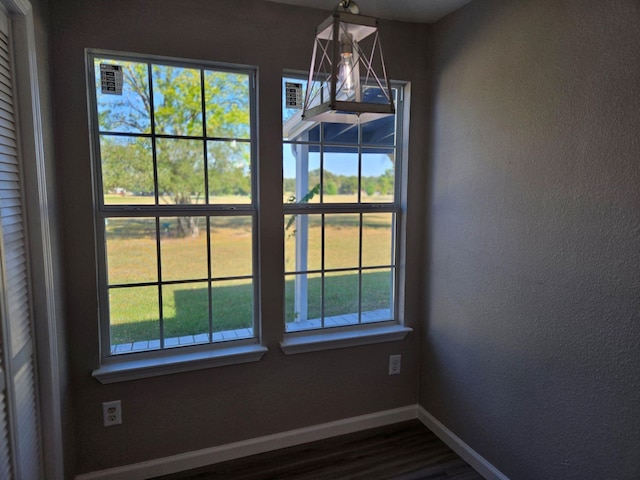 interior space with wood finished floors, a textured wall, and baseboards