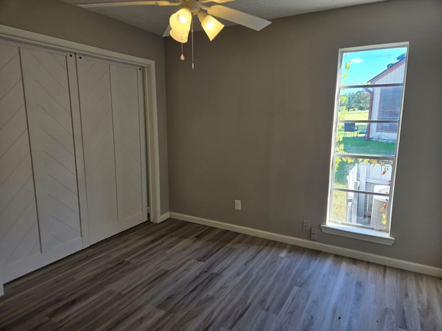 unfurnished bedroom featuring dark wood-style floors, baseboards, and multiple windows