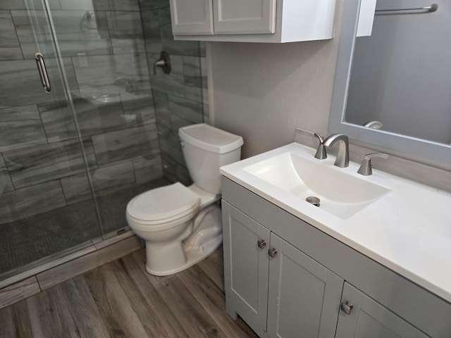 full bath featuring toilet, a shower stall, vanity, and wood finished floors