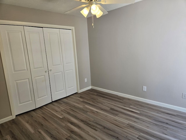 unfurnished bedroom with a closet, baseboards, ceiling fan, and dark wood-style floors