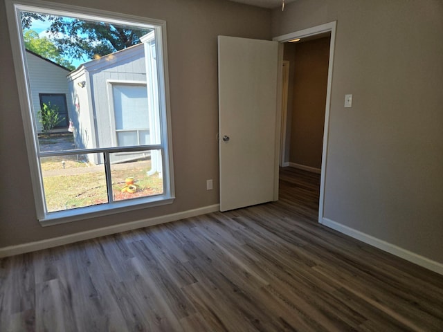 spare room with baseboards and dark wood finished floors