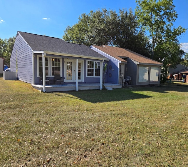 back of house with a shingled roof, french doors, and a lawn