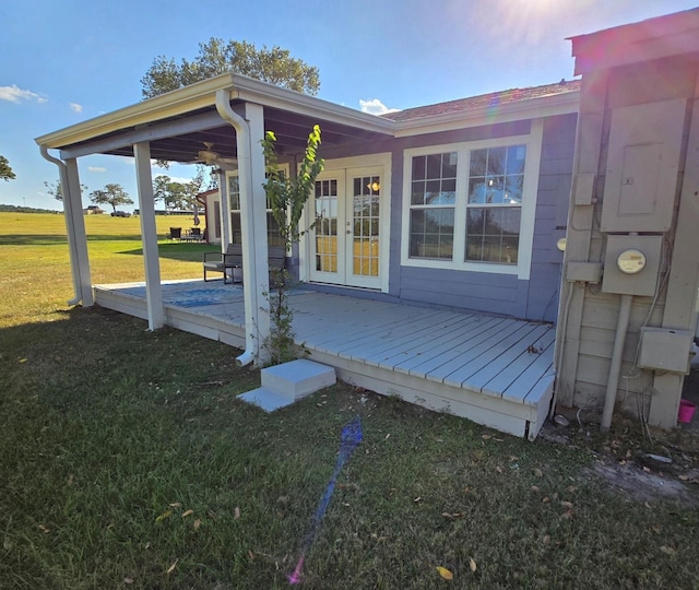view of side of home with a yard, french doors, a wooden deck, and electric panel