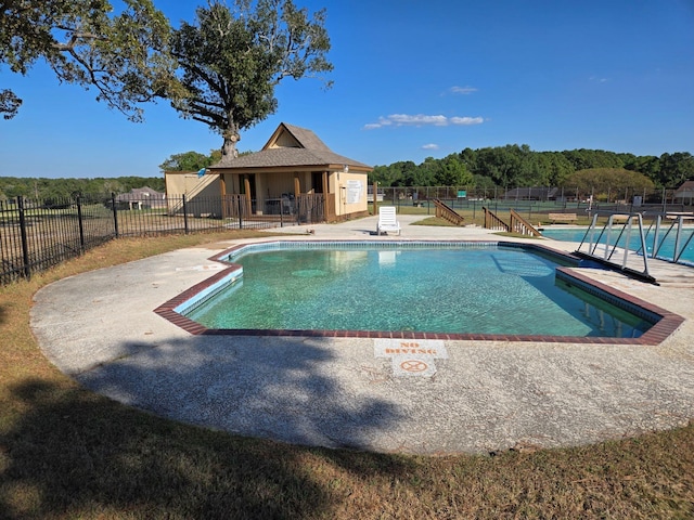 pool with a patio and fence