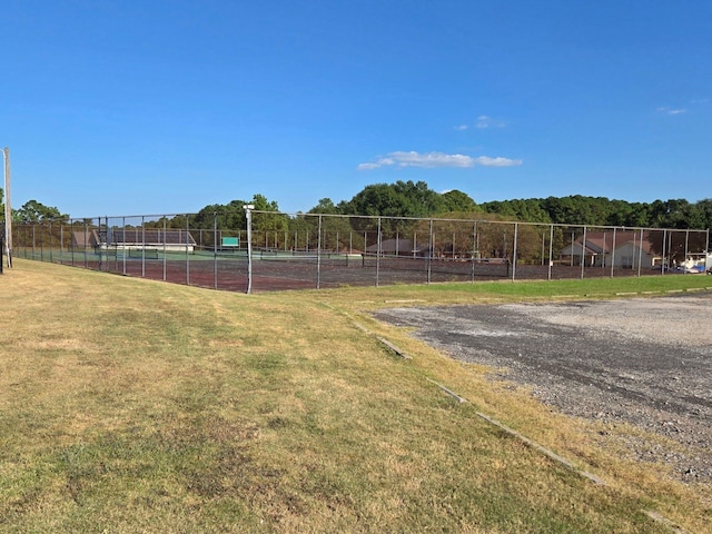view of yard with a tennis court and fence