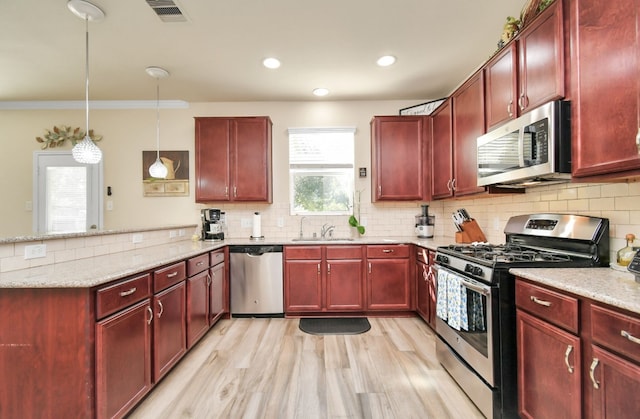 kitchen featuring hanging light fixtures, crown molding, stainless steel appliances, and plenty of natural light