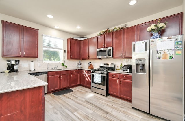 kitchen featuring light stone counters, stainless steel appliances, backsplash, and light hardwood / wood-style flooring