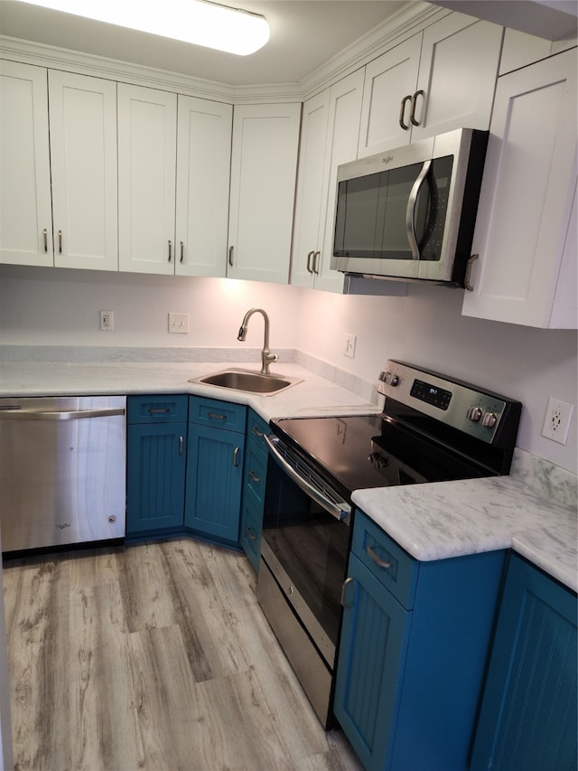 kitchen with white cabinets, sink, blue cabinetry, appliances with stainless steel finishes, and light wood-type flooring