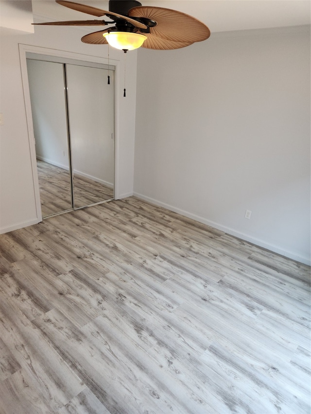 unfurnished bedroom with a closet, light hardwood / wood-style floors, and ceiling fan